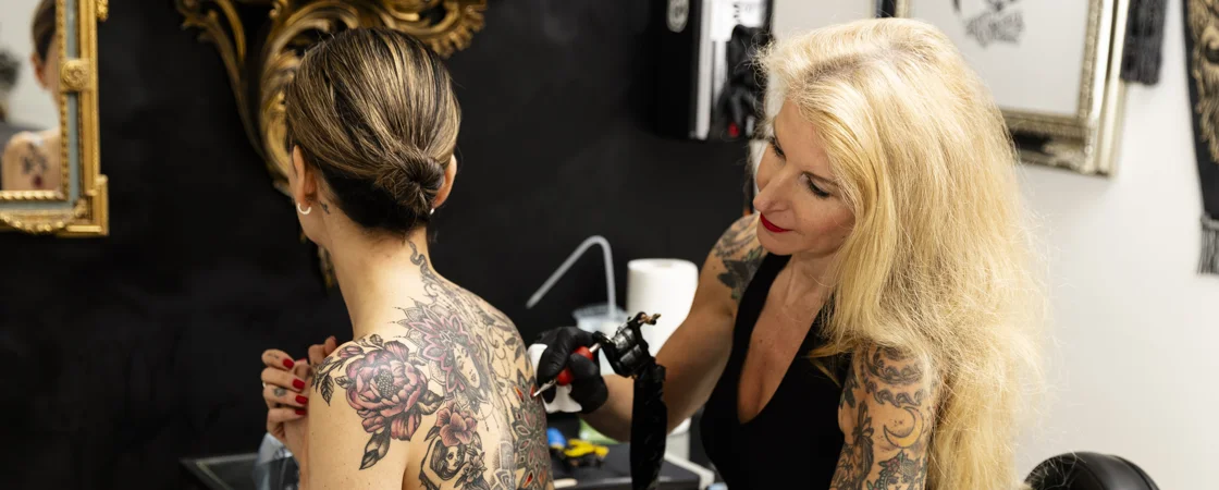 Walk-In Tattoo | Dieses Foto zeigt Monika, wie sie einer Kundin ein Tattoo auf den Rücken sticht.